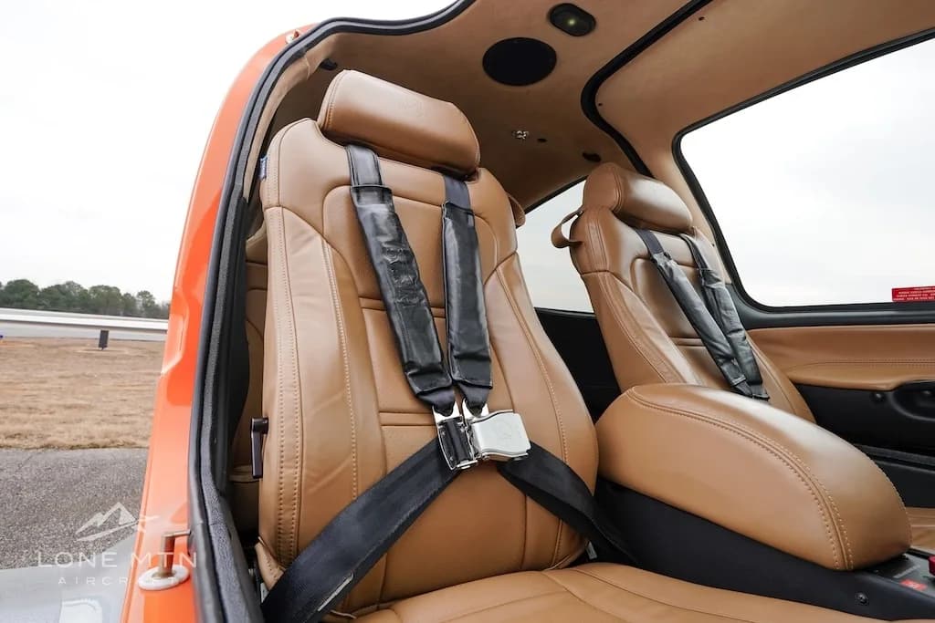 The tan leather front seats with black harnesses inside the aircraft cabin.