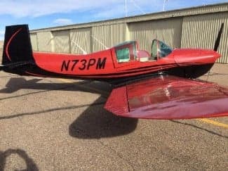 A red and black Grumman American AA-1 Yankee, registration N73PM, is parked on the tarmac.