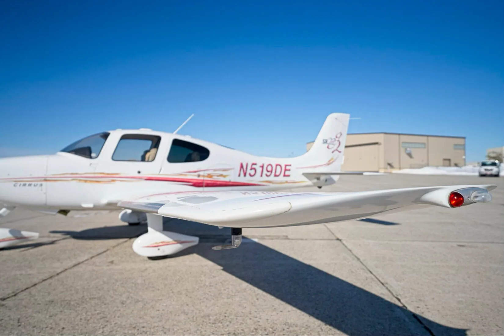 A close-up view of the right wingtip and fuselage of a white Cirrus SR22 aircraft, showing the N519DE registration.