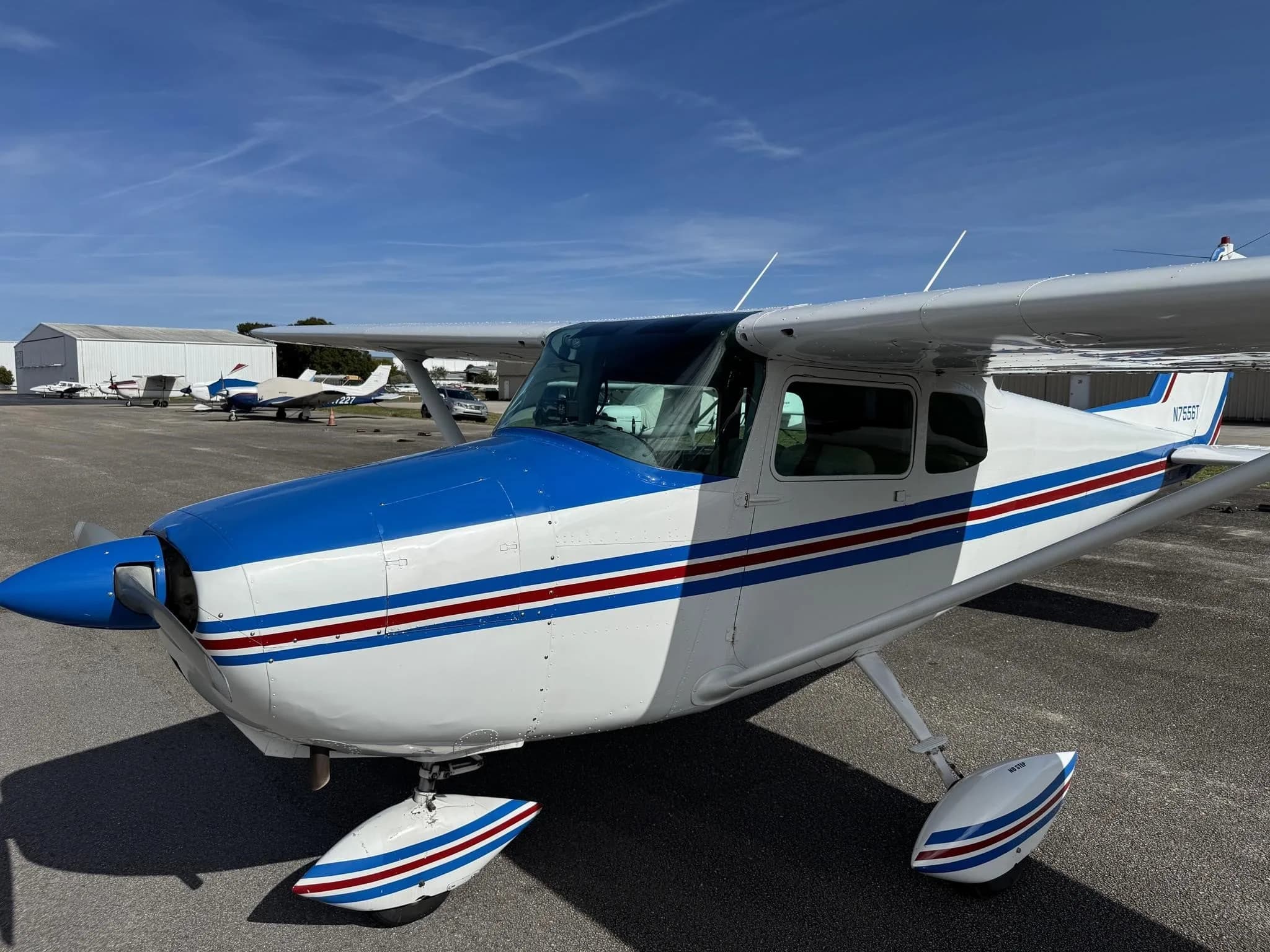 Close-up front-side view of a white and blue Cessna 172, highlighting the blue nose and stripe details.