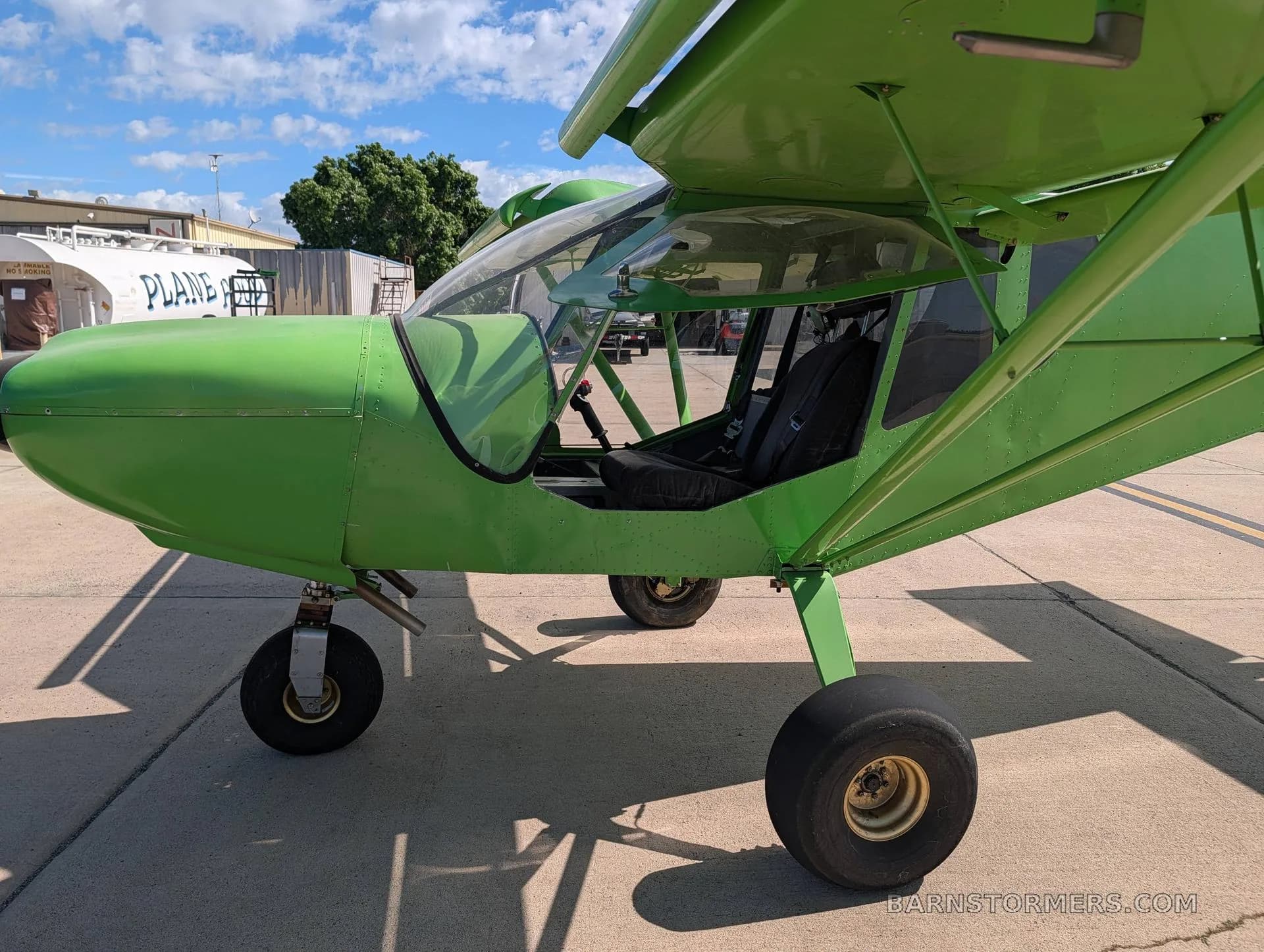 A side view of the bright green Zenith STOL CH 750 aircraft, highlighting the open canopy and landing gear.