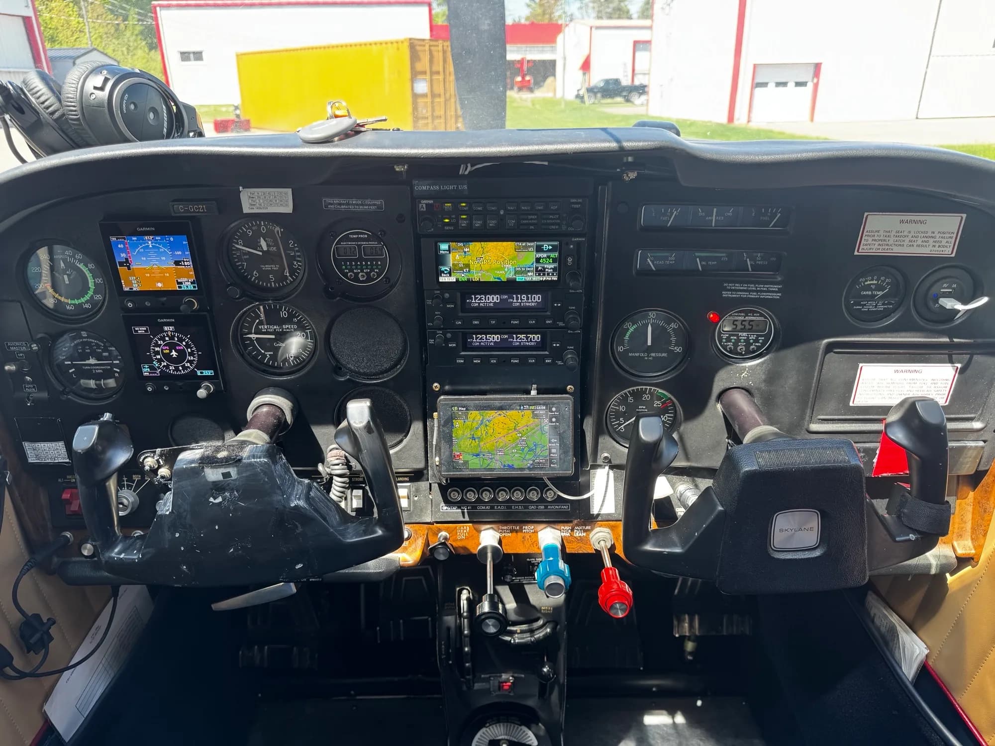 The cockpit of a Cessna Skylane, showing the instrument panel with analog gauges and modern Garmin digital displays.