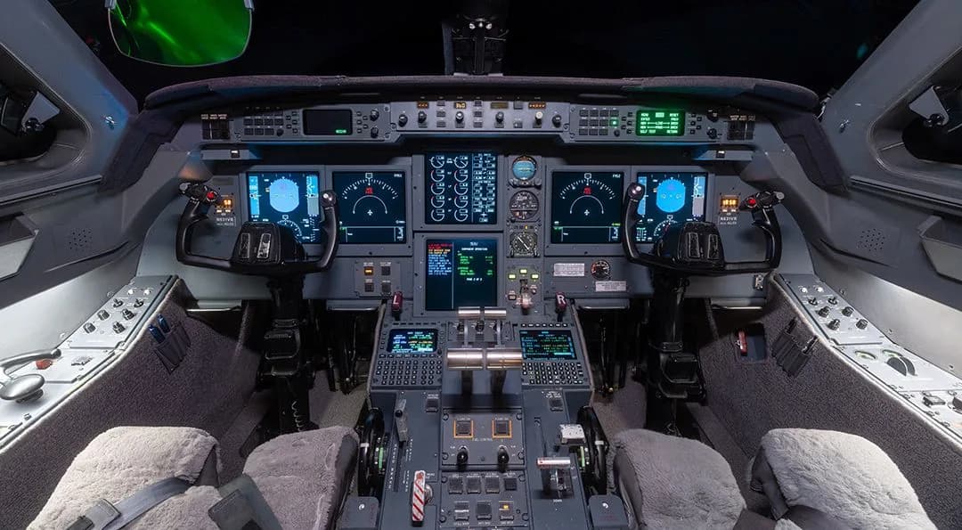 The cockpit of a Gulfstream G550 business jet, featuring multiple digital displays and control panels.