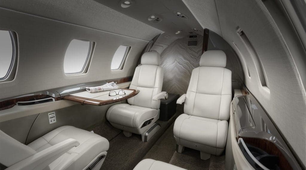The interior of a Citation M2 aircraft with leather seats and a table.