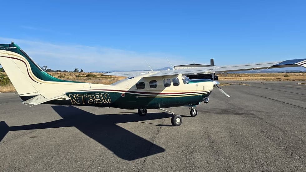 A Cessna 208 Caravan aircraft with a white and green paint scheme is parked on the tarmac.