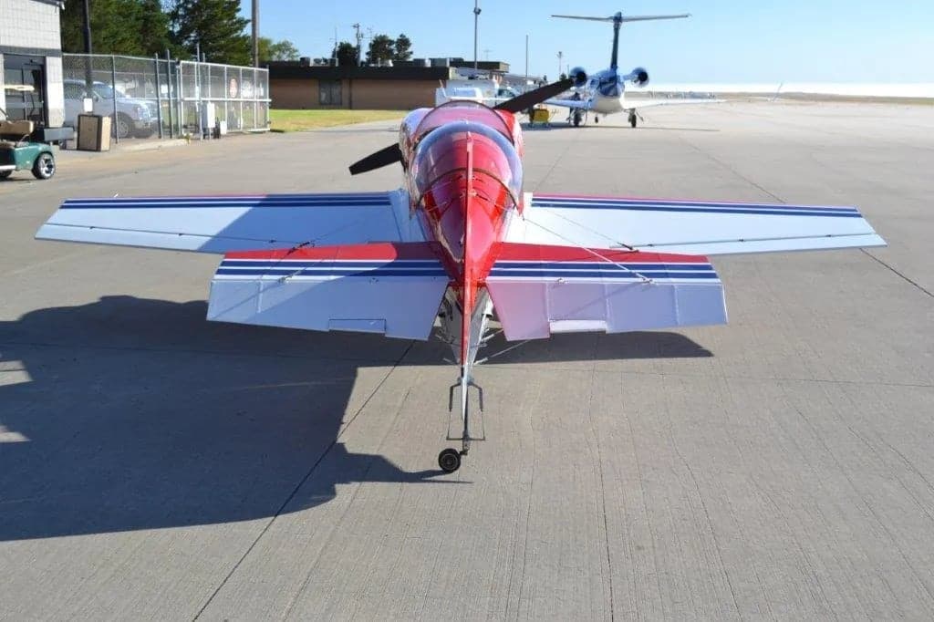 Rear view of a red and white aircraft with stars on the tail and wings parked on the tarmac.