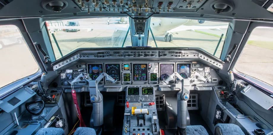 The cockpit of an Embraer Legacy aircraft, featuring multiple digital displays and control yokes.