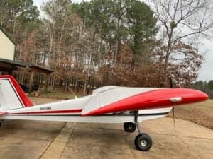A white and red aircraft is parked on a concrete surface.