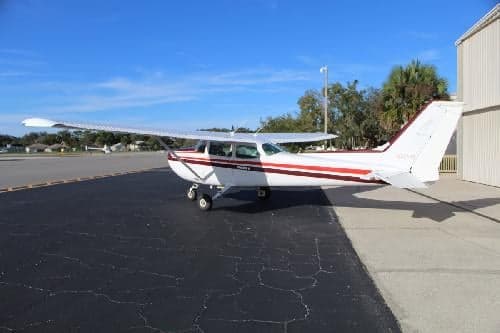 A Cessna 172 Skyhawk with a white and maroon paint scheme parked on the tarmac.
