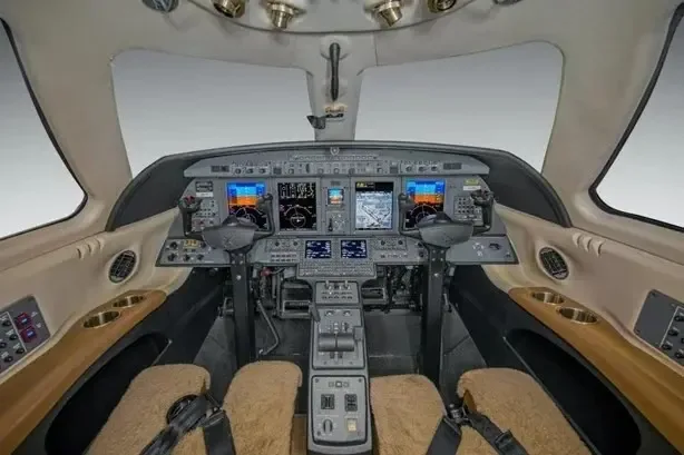 The modern cockpit of a business jet, featuring multiple digital displays and control yokes.