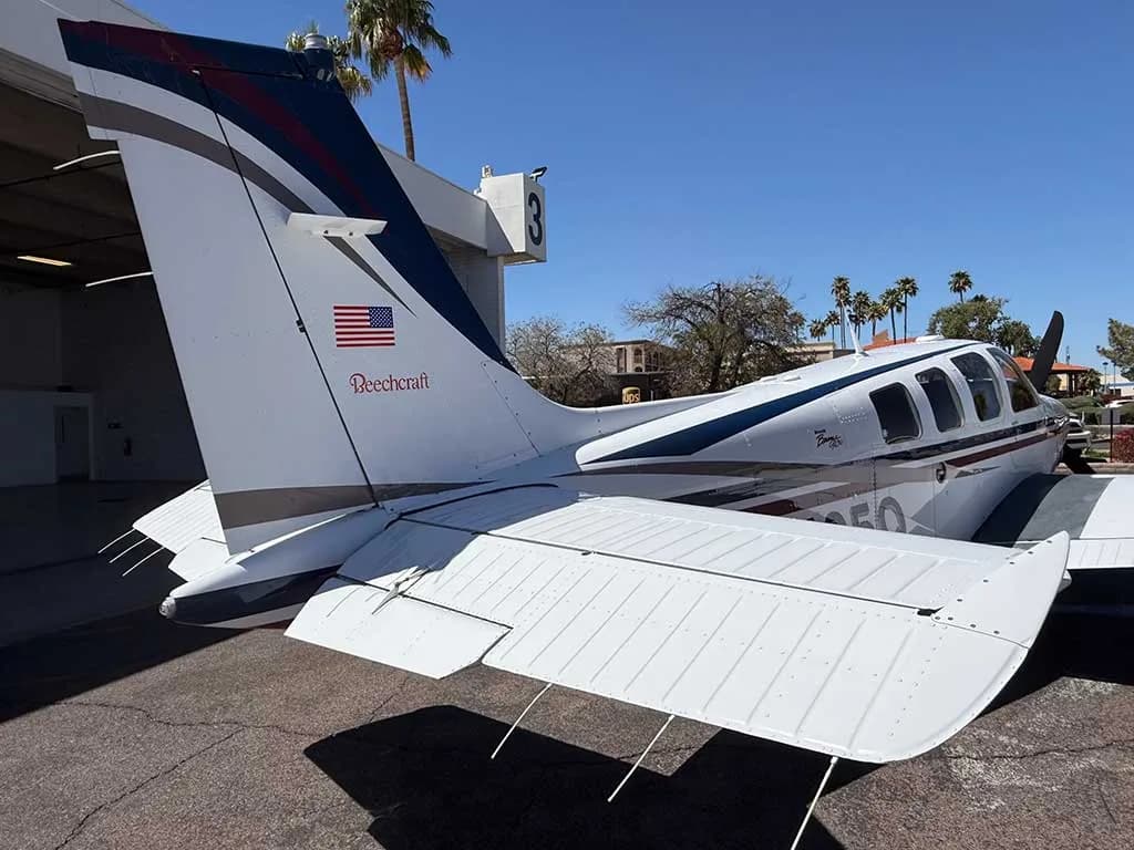A rear view of the white Beechcraft Bonanza A36, registration N25Q, showing its tail and horizontal stabilizer.