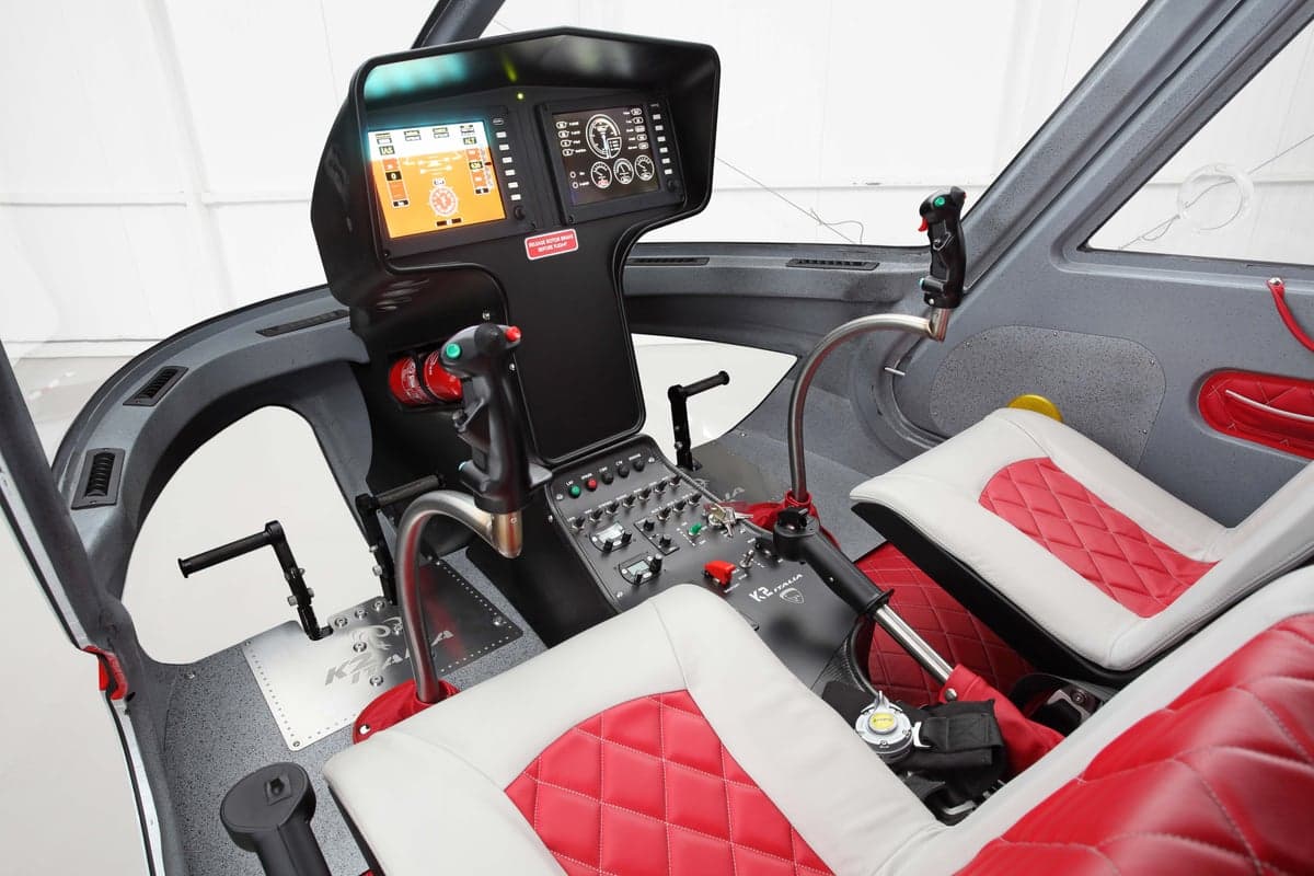 The cockpit of the helicopter features red and white seats and a modern instrument panel.