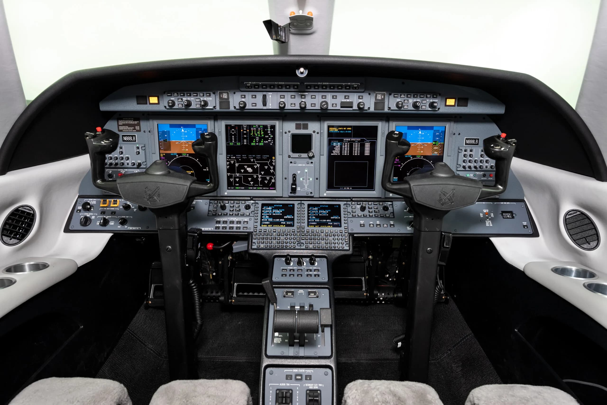The modern cockpit of a business jet, showing multiple display screens and control yokes.