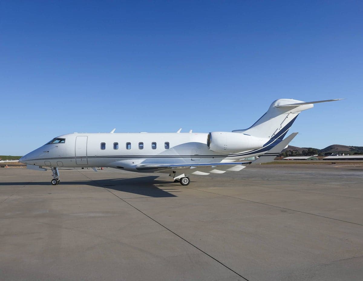 Side view of a white aircraft with blue accents parked on the tarmac.