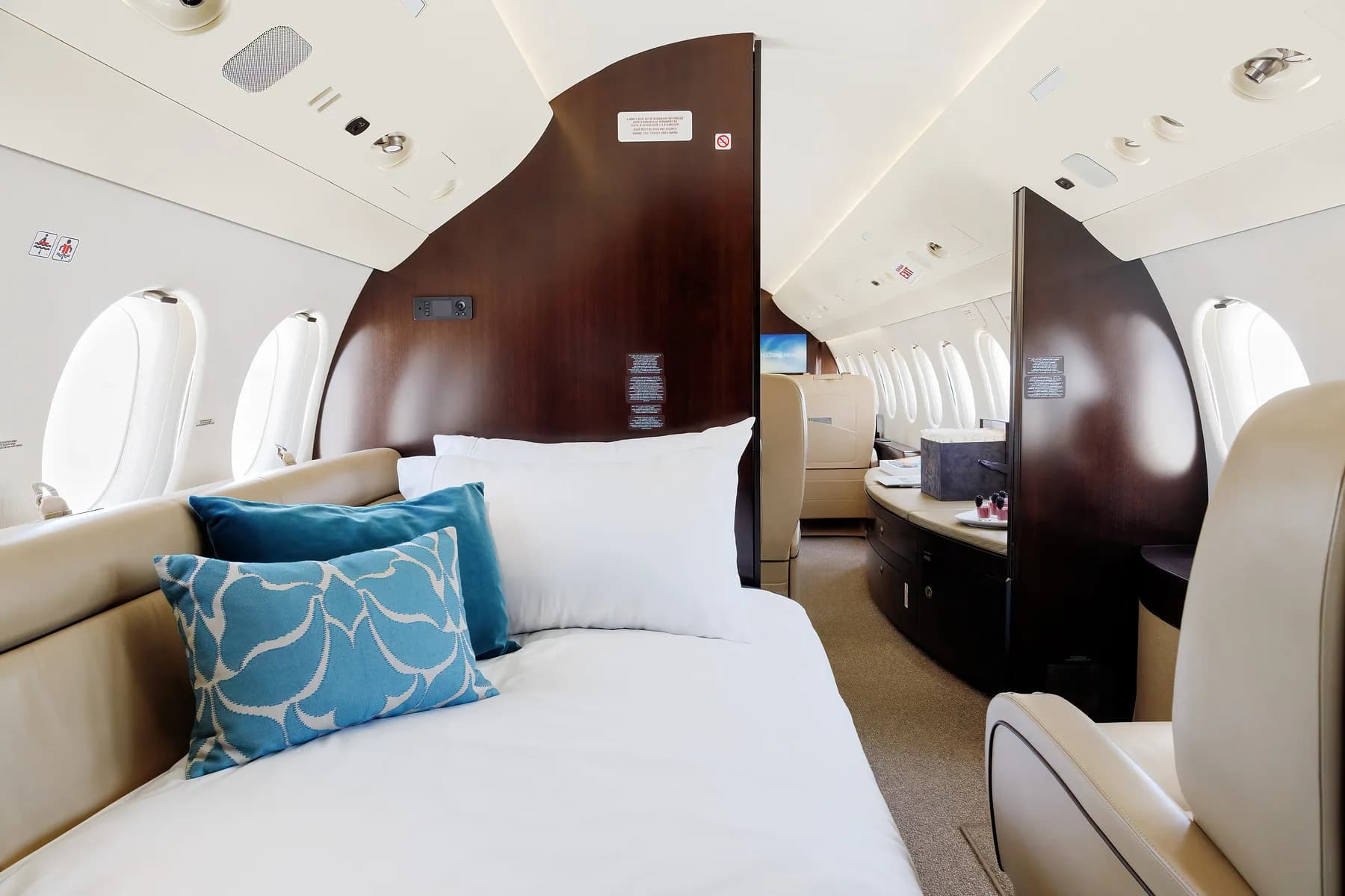 Interior of a private jet with a bed and seating area.