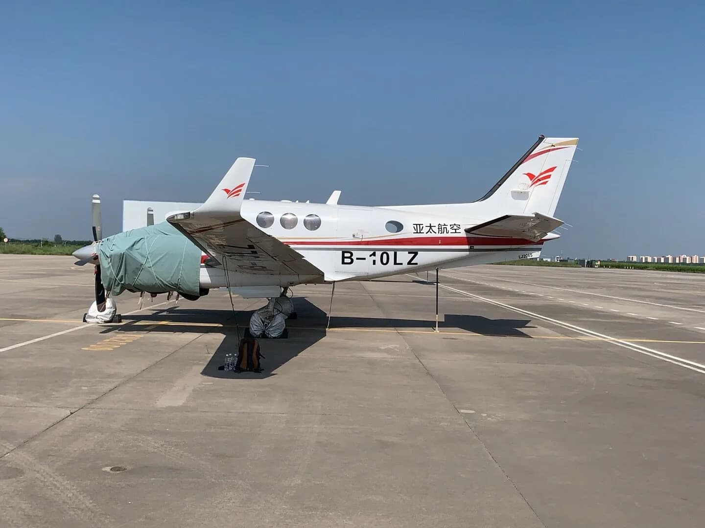 A King Air B-10LZ aircraft is parked on the tarmac with propeller covers.