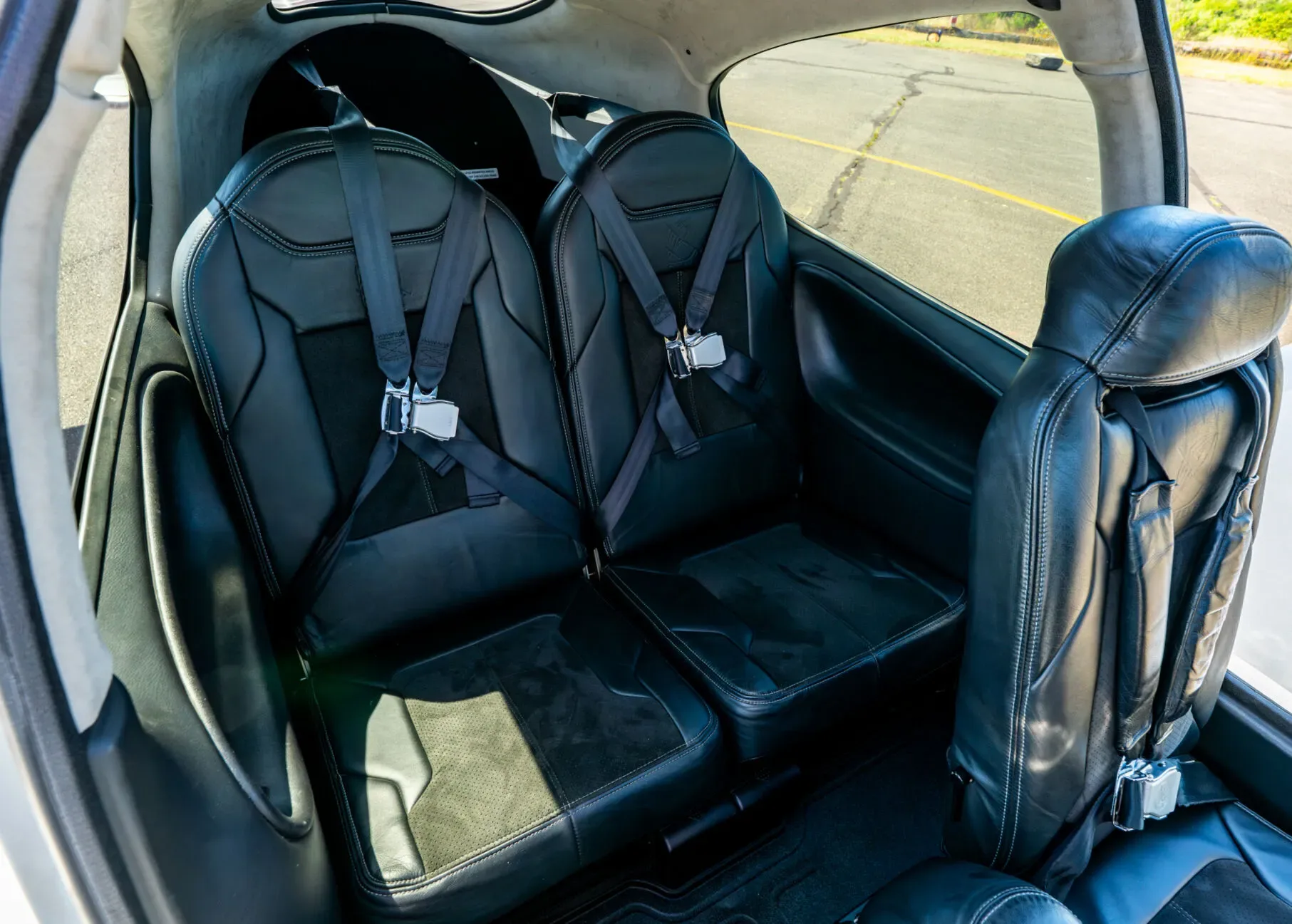 View of the black leather rear passenger seats inside the Cirrus SR22T aircraft cabin.