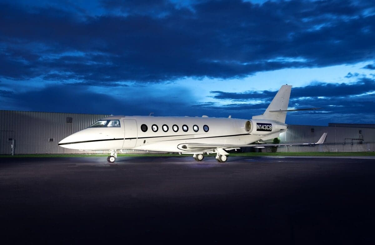Gulfstream jet parked on the tarmac at night with dramatic sky in the background.