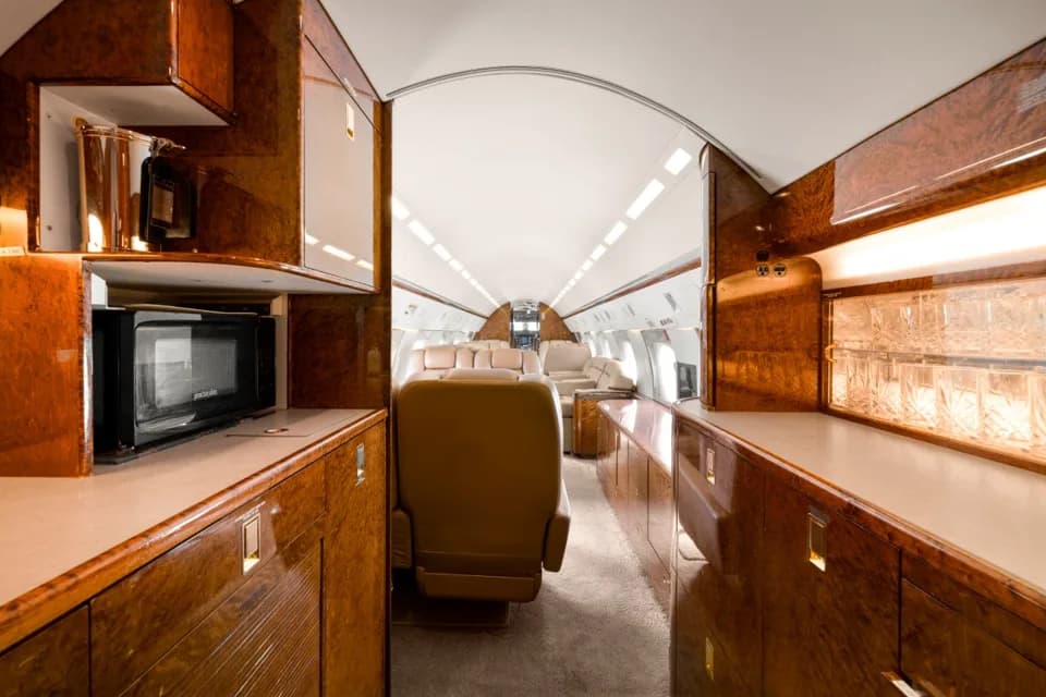 The aircraft's galley area with a microwave and polished wood cabinetry, looking towards the main cabin.