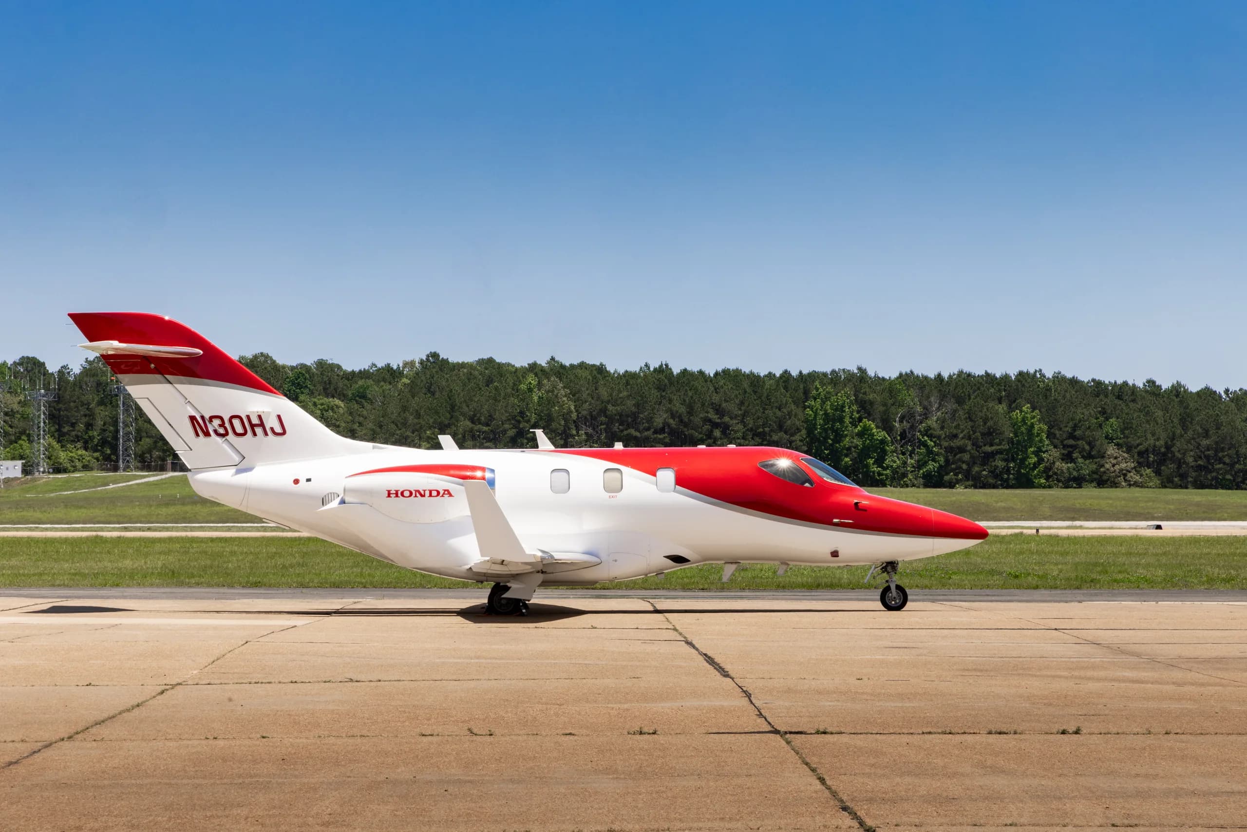 A white and red HondaJet HA-420 (N30HJ) parked on a tarmac, viewed from the right side.