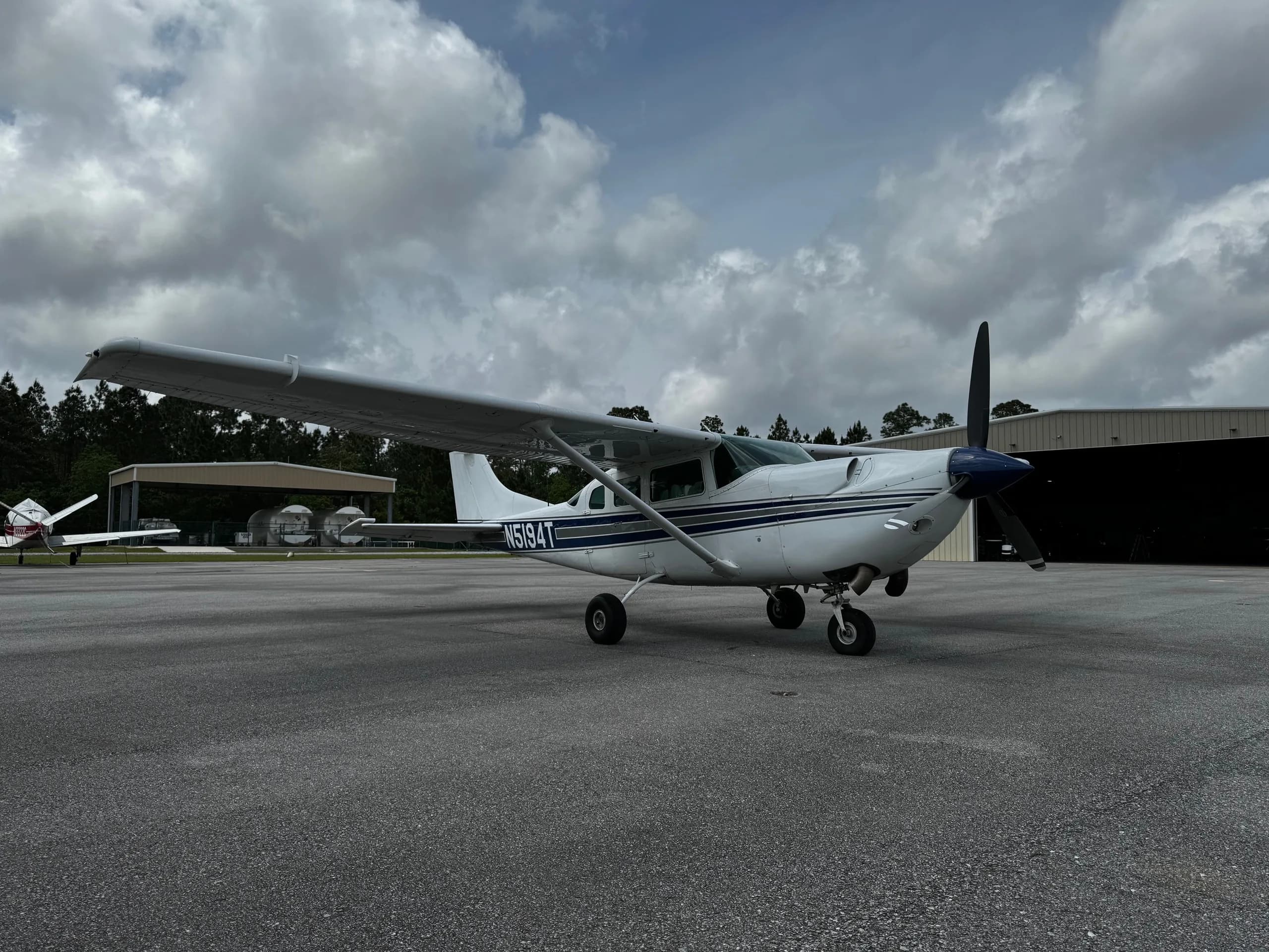 Side view of a white and blue Cessna 206 Turbo Stationair with tail number N5194T on the tarmac.