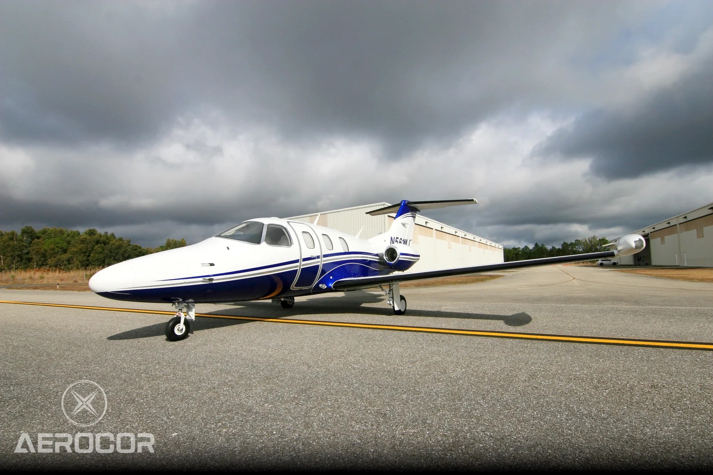 Front three-quarter view of a white and blue Eclipse 500 jet, registration N561MJ, parked on an airfield.