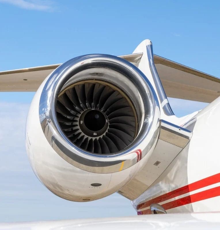 Close-up of a jet engine on a white aircraft with red stripes.