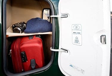 Luggage compartment with a suitcase, camera, and hat.