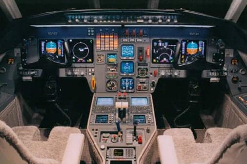 The cockpit of a business jet featuring multiple display screens and control panels.