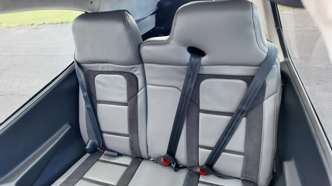 A view of the gray and dark gray rear passenger seats with seatbelts, looking towards the front of the aircraft.
