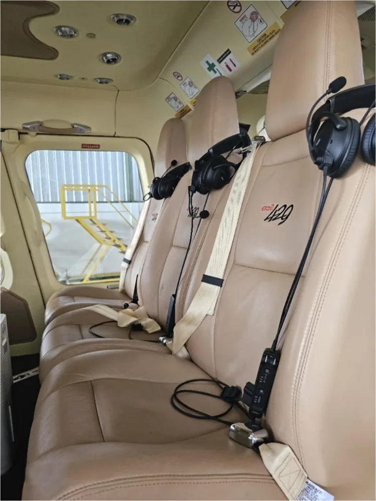 View of the helicopter cabin with tan leather seats and headsets.