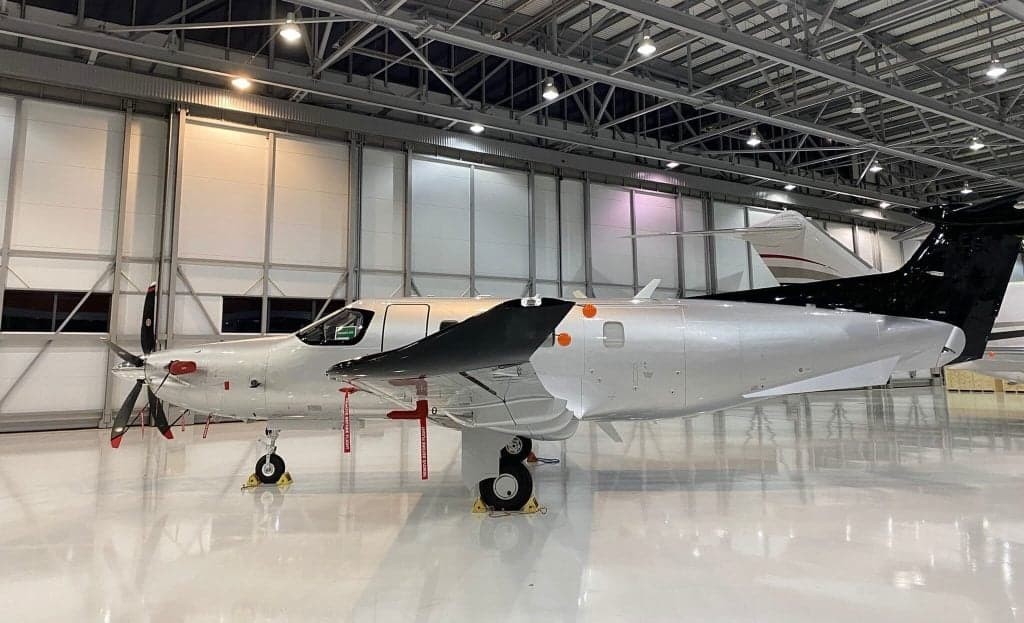A Pilatus PC-12 aircraft with registration G-MDSZ parked inside a hangar.