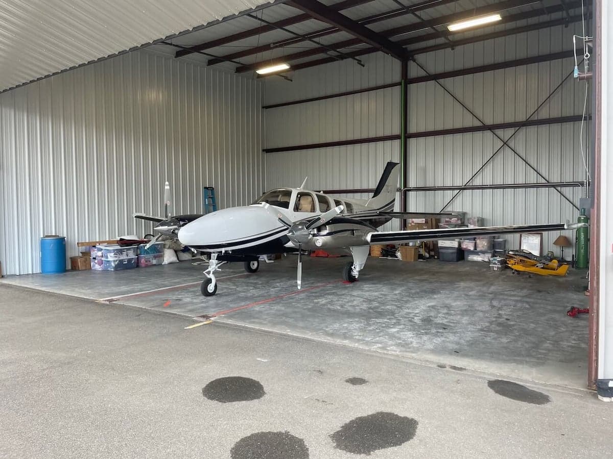 A Piper PA-31-350 Navajo Chieftain aircraft with a white and black paint scheme parked inside a hangar.