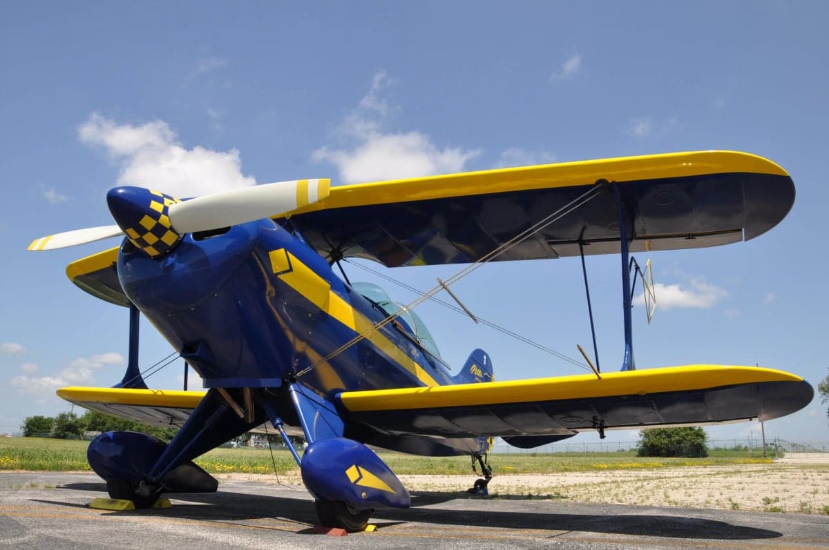 A blue and yellow biplane is parked on the tarmac.