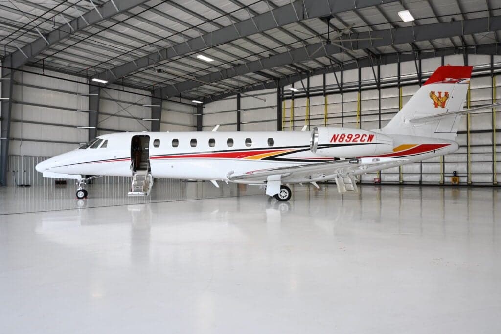 A Citation Sovereign aircraft with tail number N892CW is parked in a hangar with the door open.