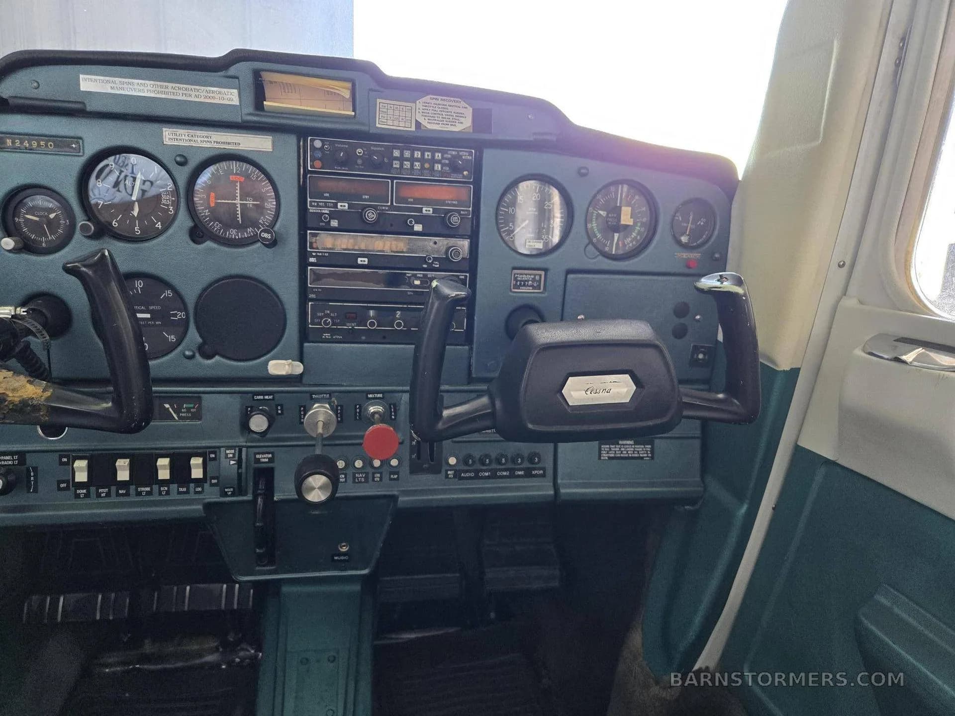 A view of the cockpit instrument panel and controls of a light aircraft, featuring analog gauges and a dark teal panel.