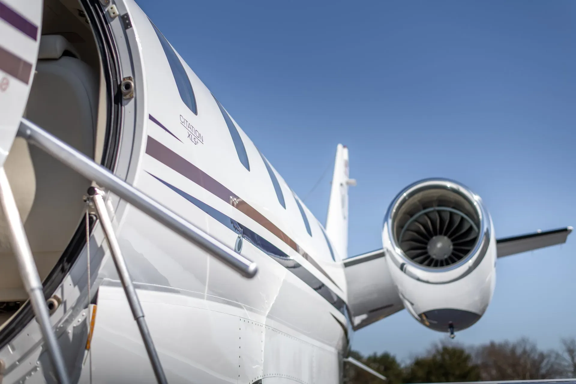 A close-up of the engine and fuselage of a white Citation XLS+ business jet.