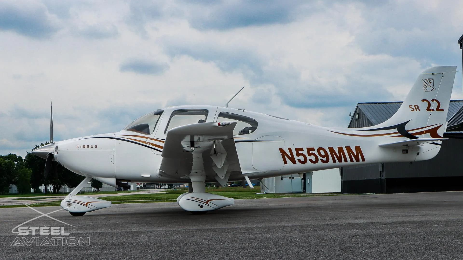 A side view of a white Cirrus SR22 aircraft with N559MM registration, showing its landing gear and wing.