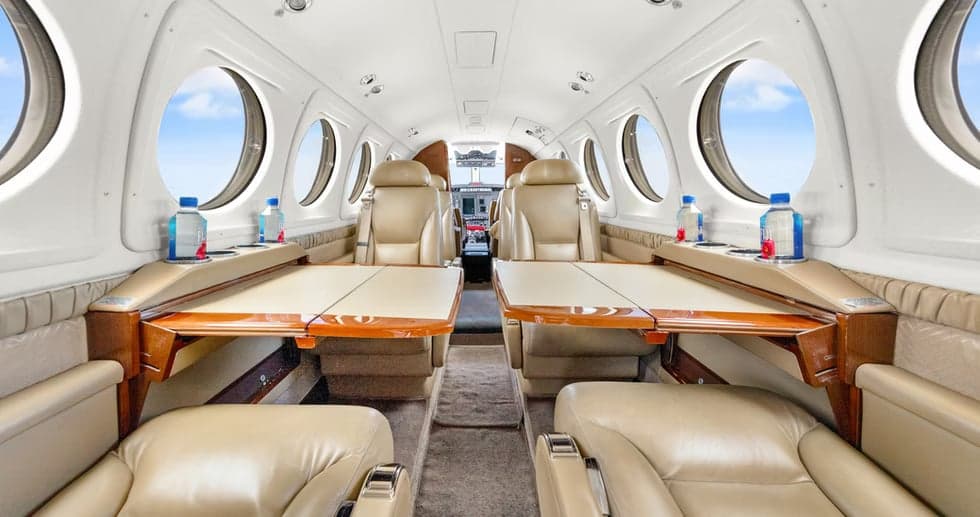 Interior view of the aircraft cabin with leather seats and tables.
