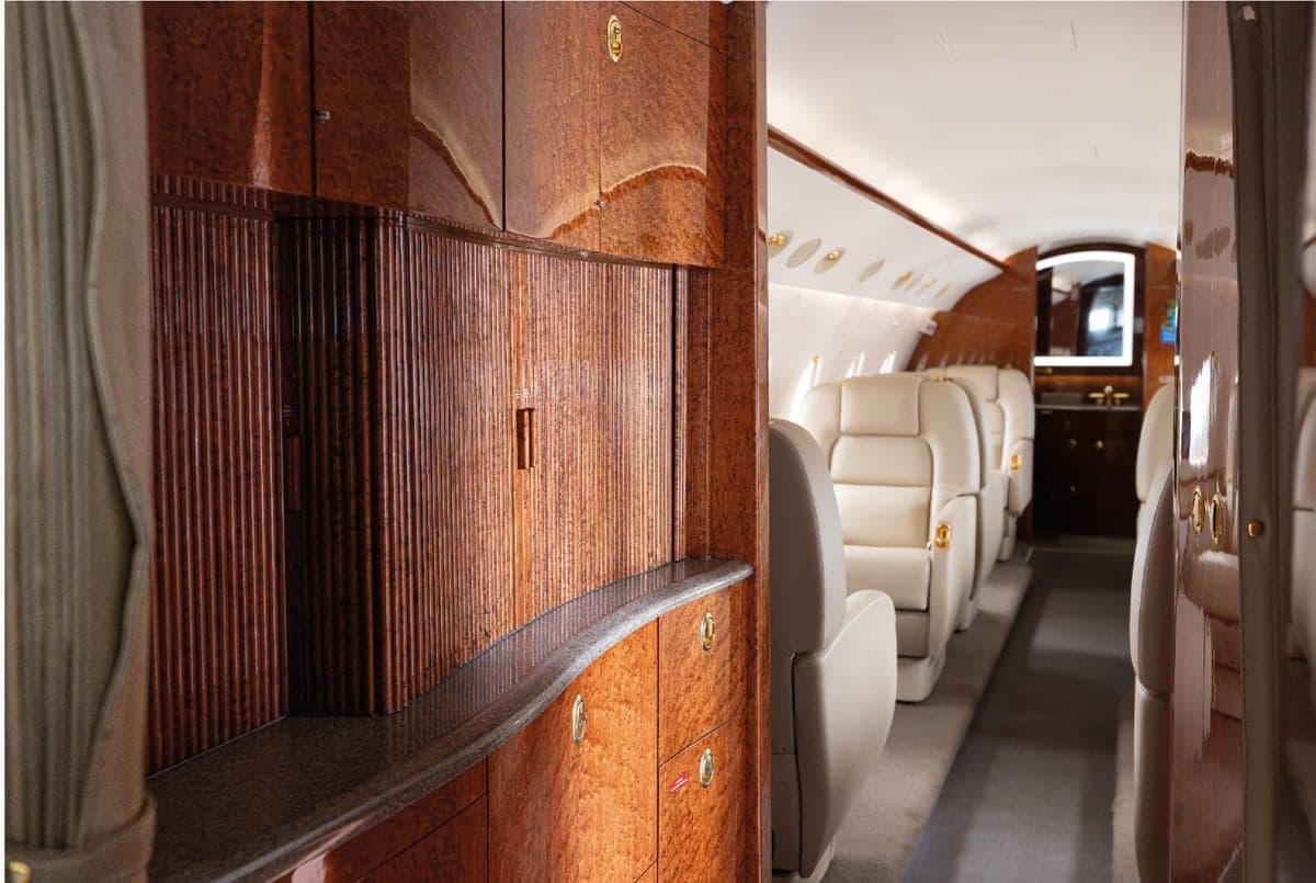 Aircraft cabin featuring leather seats and wood trim.