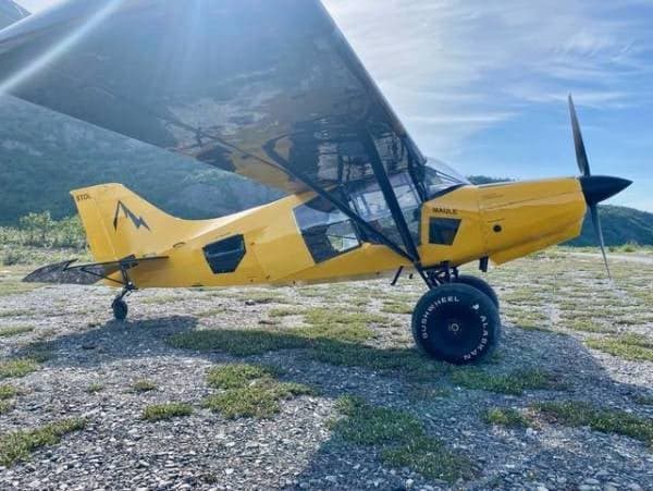 A yellow Maule aircraft is parked on a grassy field.