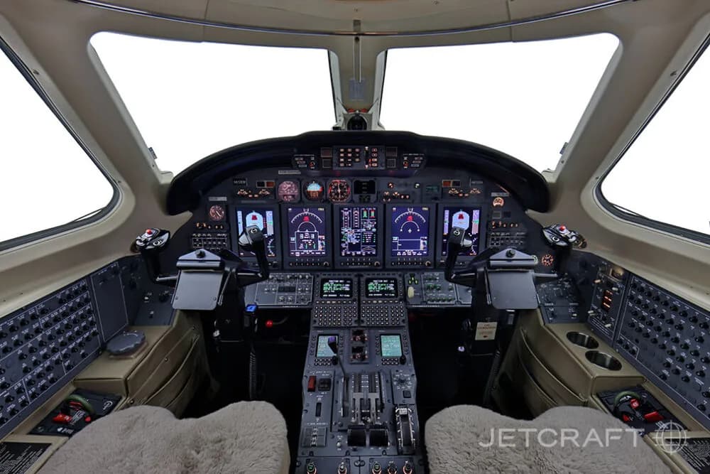 The cockpit of a business jet features a modern glass panel display and dual control yokes.