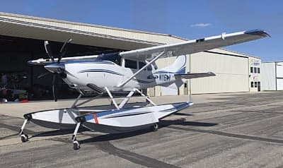 A Quest Kodiak aircraft on floats is parked outside a hangar.