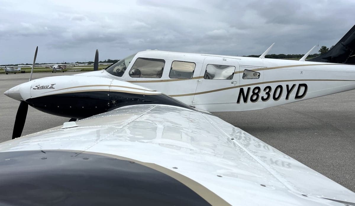 Close up of the wing and fuselage of a Piper Seneca II aircraft with a white and black paint scheme.