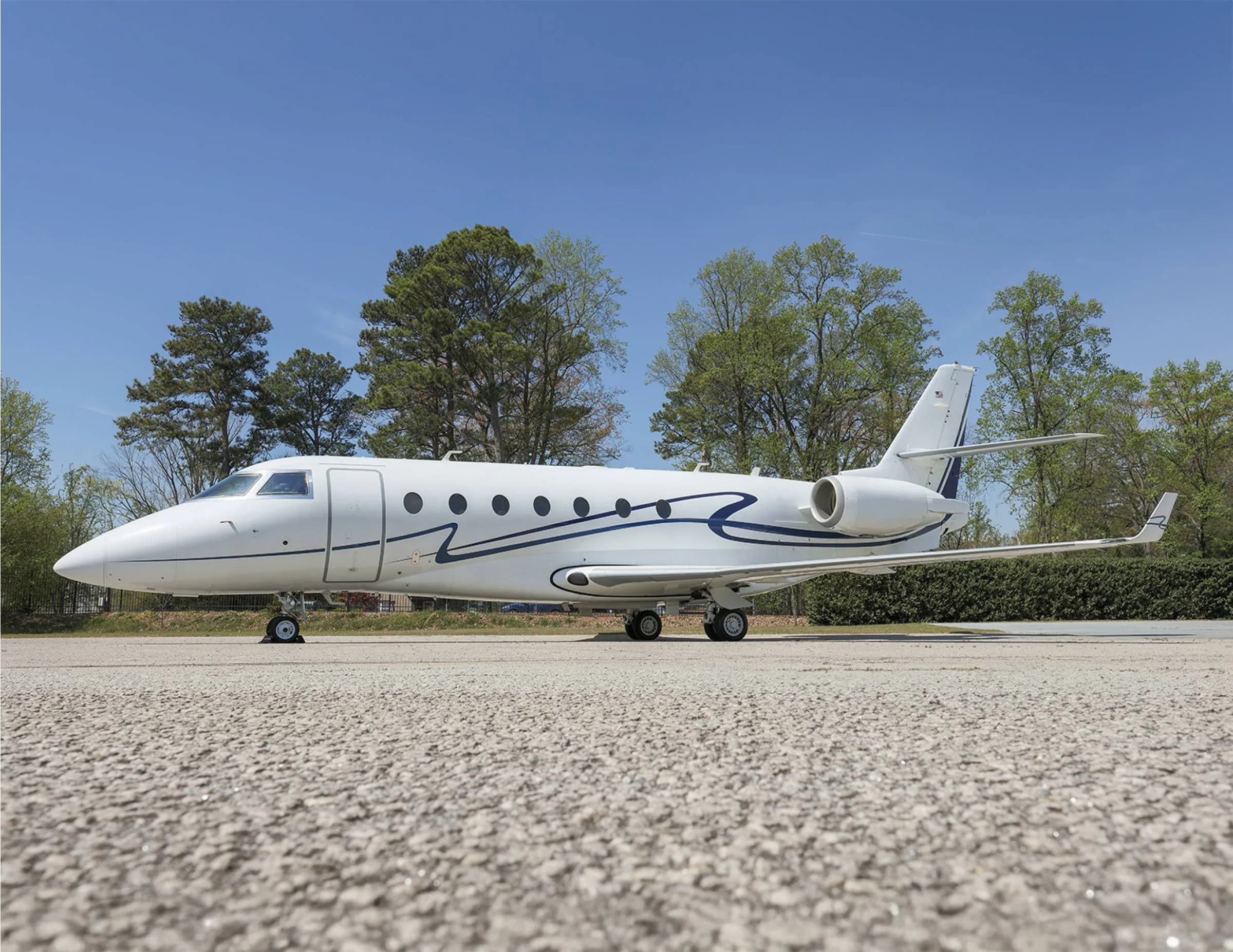 Side view of a white aircraft with blue accents parked on the tarmac.