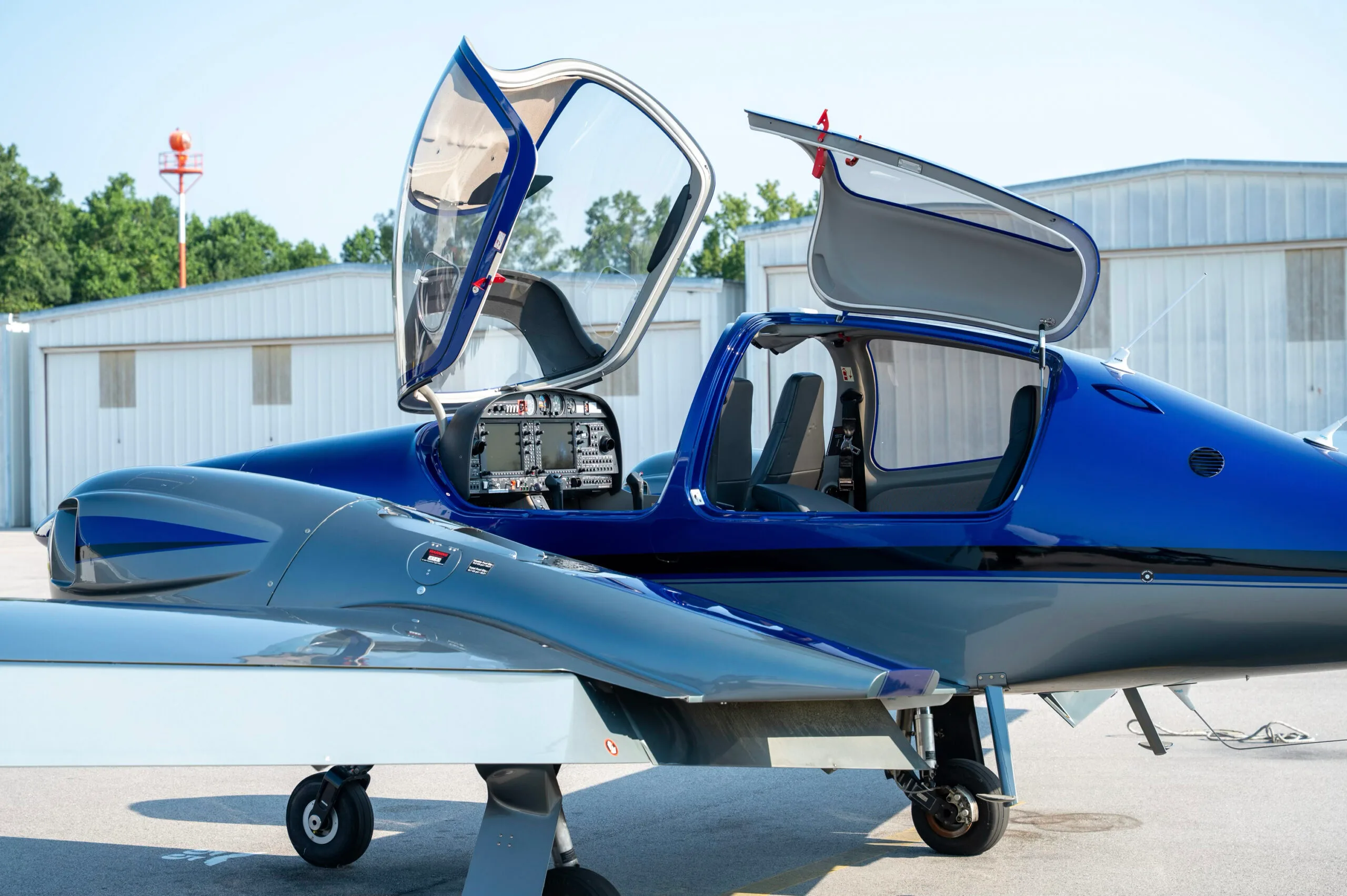 Close-up of the open doors and cockpit of a blue and grey Diamond DA42 aircraft.