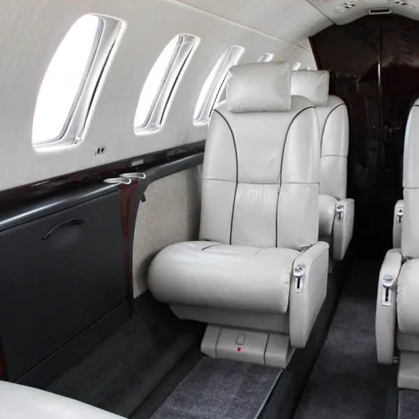 Side view of the aircraft cabin showing light-colored leather seats and windows.