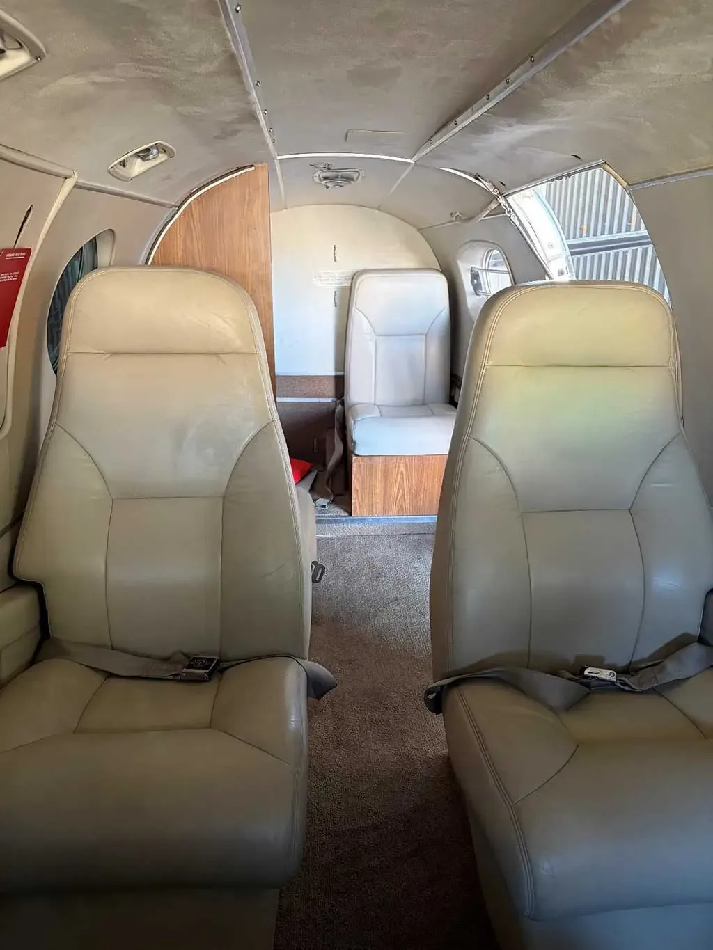 The interior cabin of a Beechcraft King Air C90, showing two beige leather seats facing the rear of the aircraft.