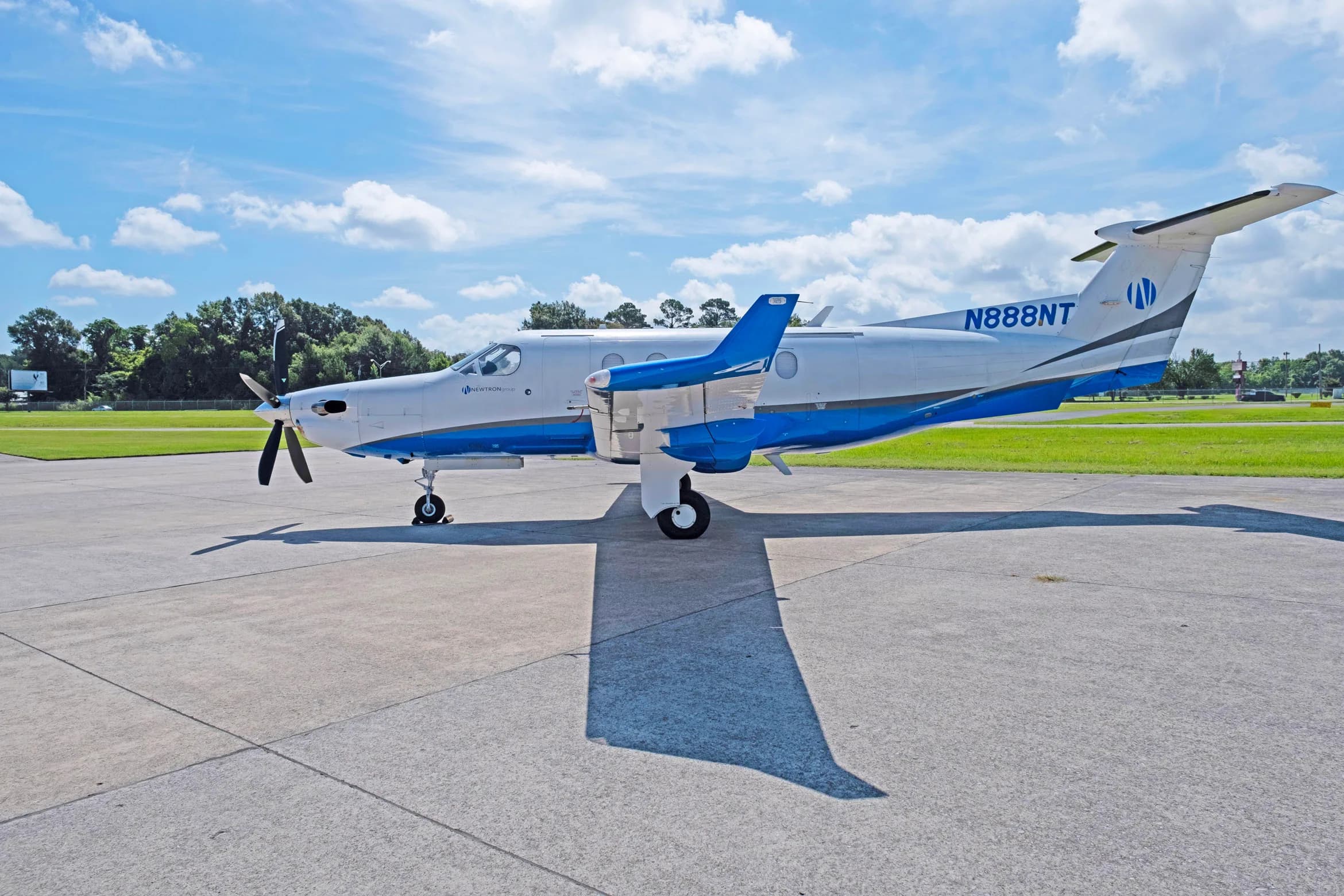 A white and blue Pilatus PC-12 aircraft, tail number N888NT, parked on a tarmac showing the right side.