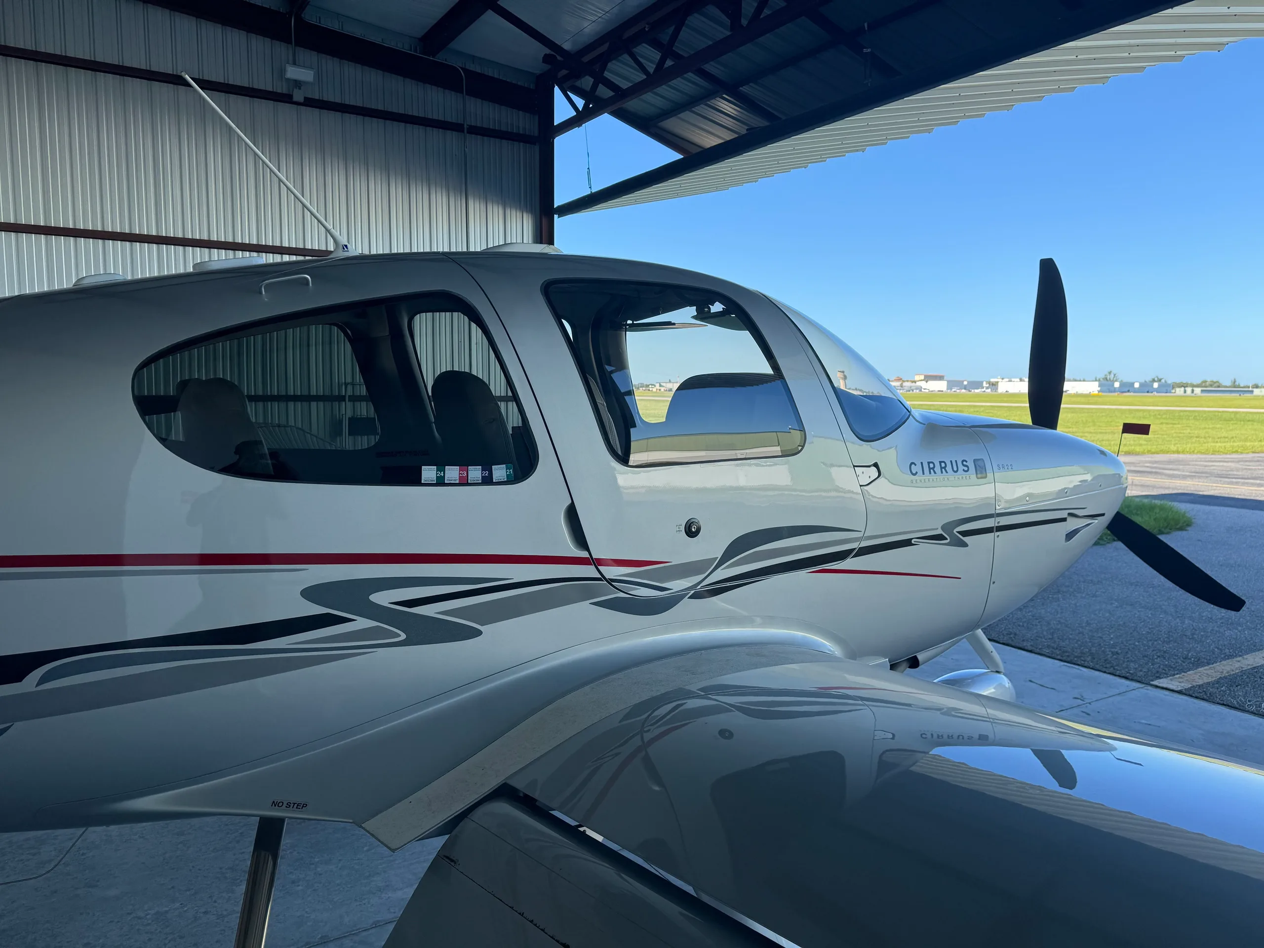 A close-up view of the front-right fuselage of a silver Cirrus SR22 Generation Three aircraft with N380SR registration, parked in a hangar.